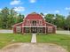 Striking barn-style home featuring a red exterior, white trim, covered porch, and manicured lawn at 925 Hamilton Rd, Chester, SC 29706
