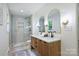 Bright bathroom featuring double vanity, wooden cabinets, and modern shower with glass door and gold trim at 9520 Squirrel Hollow Ln, Charlotte, NC 28270