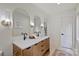 Bright bathroom featuring double vanity with modern light fixtures, wooden cabinets, and stylish arched mirrors at 9520 Squirrel Hollow Ln, Charlotte, NC 28270