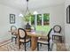 Elegant dining room with a wooden table set, modern lighting, and a view of the green backyard at 9520 Squirrel Hollow Ln, Charlotte, NC 28270