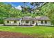 Charming single-story home featuring lush green lawn, mature trees, and a manicured landscape at 9520 Squirrel Hollow Ln, Charlotte, NC 28270