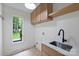Well-lit laundry room featuring a deep sink, marble countertops, and built-in overhead cabinets at 9520 Squirrel Hollow Ln, Charlotte, NC 28270