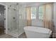 This stylish bathroom boasts a sleek soaking tub, glass-enclosed shower, and a window for plenty of natural light at 10327 Shelter Rock Ct, Charlotte, NC 28214