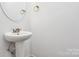 Clean half bathroom with pedestal sink, mirror and modern flooring at 1218 Rosada Dr, Charlotte, NC 28213