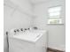 Bright laundry room featuring a white Whirlpool washer and dryer, with ample shelving and natural light from the window at 1218 Rosada Dr, Charlotte, NC 28213