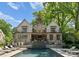 Backyard pool view showcasing a well-maintained pool, seating area, and the home's stone exterior at 1550 Queens W Rd, Charlotte, NC 28207