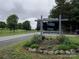 Welcome to Pinehaven Village, a voluntary HOA community entrance with a decorative sign, flowers, and rock border at 189 6Th Ave, New London, NC 28127