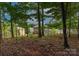 View of a brown two-story house through trees and foliage in the surrounding wooded area at 1919 Madeira Cir, Waxhaw, NC 28173