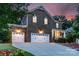 Charming two-story brick home featuring a three-car garage and well-manicured lawn at dusk at 1919 Madeira Cir, Waxhaw, NC 28173