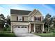 Charming two-story home featuring a covered front porch, attached garage, and beautifully landscaped front yard at 20392 Queens St, Cornelius, NC 28031