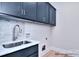 Laundry area showcasing modern gray cabinetry, a marble countertop, and stainless steel sink at 20392 Queens St, Cornelius, NC 28031