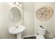 Stylish half bath featuring a pedestal sink, oval mirror and decorative wall art at 220 Glenville Dr, Fort Mill, SC 29715