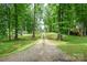 Long gravel driveway leading to a charming home nestled in a lush, green, wooded area at 327 Holly Dr, Mount Holly, NC 28120