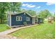 Side view of blue house featuring attractive landscaping and a charming well at 327 Holly Dr, Mount Holly, NC 28120
