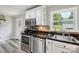 A well-lit kitchen features white cabinets, stainless appliances, and black countertops at 327 Holly Dr, Mount Holly, NC 28120