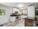 The bright kitchen features white cabinets, stainless steel appliances, and wood-look flooring at 327 Holly Dr, Mount Holly, NC 28120