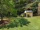 Beautiful backyard with shed surrounded by green grass, mature trees, and privacy fence at 389 Ponderosa Cir, Mooresville, NC 28117