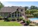 View of brick home backyard with sunroom addition and fenced pool with mature landscaping at 389 Ponderosa Cir, Mooresville, NC 28117