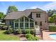 View of brick home backyard with sunroom addition and fenced pool with mature landscaping at 389 Ponderosa Cir, Mooresville, NC 28117