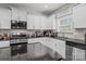 Bright kitchen with white cabinets, granite countertops, stainless steel appliances, and a modern backsplash at 413 Wheat Field Dr, Mount Holly, NC 28120