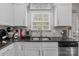 Close-up of the kitchen featuring white cabinets, granite countertops, and stainless steel appliances at 413 Wheat Field Dr, Mount Holly, NC 28120