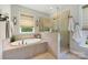 Bright bathroom with soaking tub, glass shower, and neutral tile at 4151 Green Park Ct, Harrisburg, NC 28075