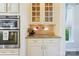 Close-up shot of butler's pantry area with glassware, granite counter, and stainless steel appliances at 4151 Green Park Ct, Harrisburg, NC 28075