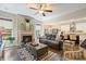 Comfortable living room with a fireplace, ceiling fan, large windows, and an opening to the kitchen at 4151 Green Park Ct, Harrisburg, NC 28075