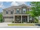 Inviting two-story home featuring stone accents, gray siding, a well-manicured lawn, and a charming front porch at 515 Lizzie Ln, Fort Mill, SC 29708