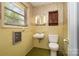 Bathroom featuring yellow tiling, floral wallpaper, sink, toilet, and window with natural light at 52 September Ct, Concord, NC 28025
