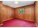 Bedroom with wood paneled walls, red carpet, and a window looking out onto a green space at 52 September Ct, Concord, NC 28025