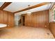 Living room featuring wood paneling, brick floors, a vintage chandelier, and access to other rooms in the house at 52 September Ct, Concord, NC 28025