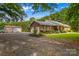 Brick home with a detached garage, featuring a well-kept lawn, mature trees, and a gravel driveway at 648 Odell School Rd, Concord, NC 28027