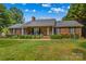 Classic brick home featuring a covered porch, an American flag, and a green lawn at 648 Odell School Rd, Concord, NC 28027