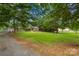 Spacious front yard with mature trees and a well-maintained lawn, leading to a brick home at 648 Odell School Rd, Concord, NC 28027