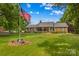 Charming brick home featuring a well-manicured lawn, lush landscaping, and a prominent American flag display at 648 Odell School Rd, Concord, NC 28027