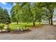 Landscaped front yard with green trees and a decorative wishing well feature at 648 Odell School Rd, Concord, NC 28027