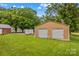 Detached two-car garage on a large grassy lot with mature trees on a sunny day at 648 Odell School Rd, Concord, NC 28027