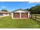 Detached two-car garage with brown doors and a neat yard, adjacent to the main house at 9135 Stokes Ferry Rd, Salisbury, NC 28146