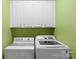 Laundry room with white washer and dryer and white cabinets against a lime green painted wall at 10405 Scotland Ave, Indian Land, SC 29707