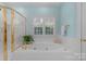 Bathroom featuring a large white tub next to a gold-trimmed shower, illuminated by natural light from a window at 10508 Old Wayside Rd, Charlotte, NC 28277