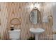 Stylish powder room with decorative wallpaper, pedestal sink, and decorative oval mirror at 10508 Old Wayside Rd, Charlotte, NC 28277