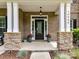 Inviting front porch with stylish stone columns, a black door, and decorative planters at 10800 Alabaster Dr, Davidson, NC 28036