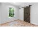 A bedroom features a barn door, a window with blinds, and light-colored walls and floor at 110 Lambert Ln, Statesville, NC 28677