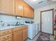 A classic laundry room includes a sink, cabinets, washer, and dryer at 202 Cameron Dr, Kings Mountain, NC 28086