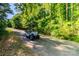 Scenic view of a golf cart on a paved path surrounded by lush greenery and trees in the Atherton community at 324 Squash Harvest Ct, Matthews, NC 28104