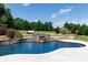 Backyard showcasing an in-ground pool with a stone water feature, surrounded by lush landscaping at 324 Squash Harvest Ct, Matthews, NC 28104