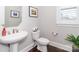 Stylish powder room with a pedestal sink, toilet, modern fixtures, wood floors, and plantation shutters at 324 Squash Harvest Ct, Matthews, NC 28104