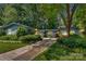 Beautiful exterior with mature trees, lush landscaping, driveway, and a painted, yellow front door at 331 Glen Oaks Rd, Charlotte, NC 28270