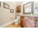Charming powder room featuring a decorative mirror, granite countertop, wood cabinets, and hardwood floors at 4319 Sailview Dr, Denver, NC 28037